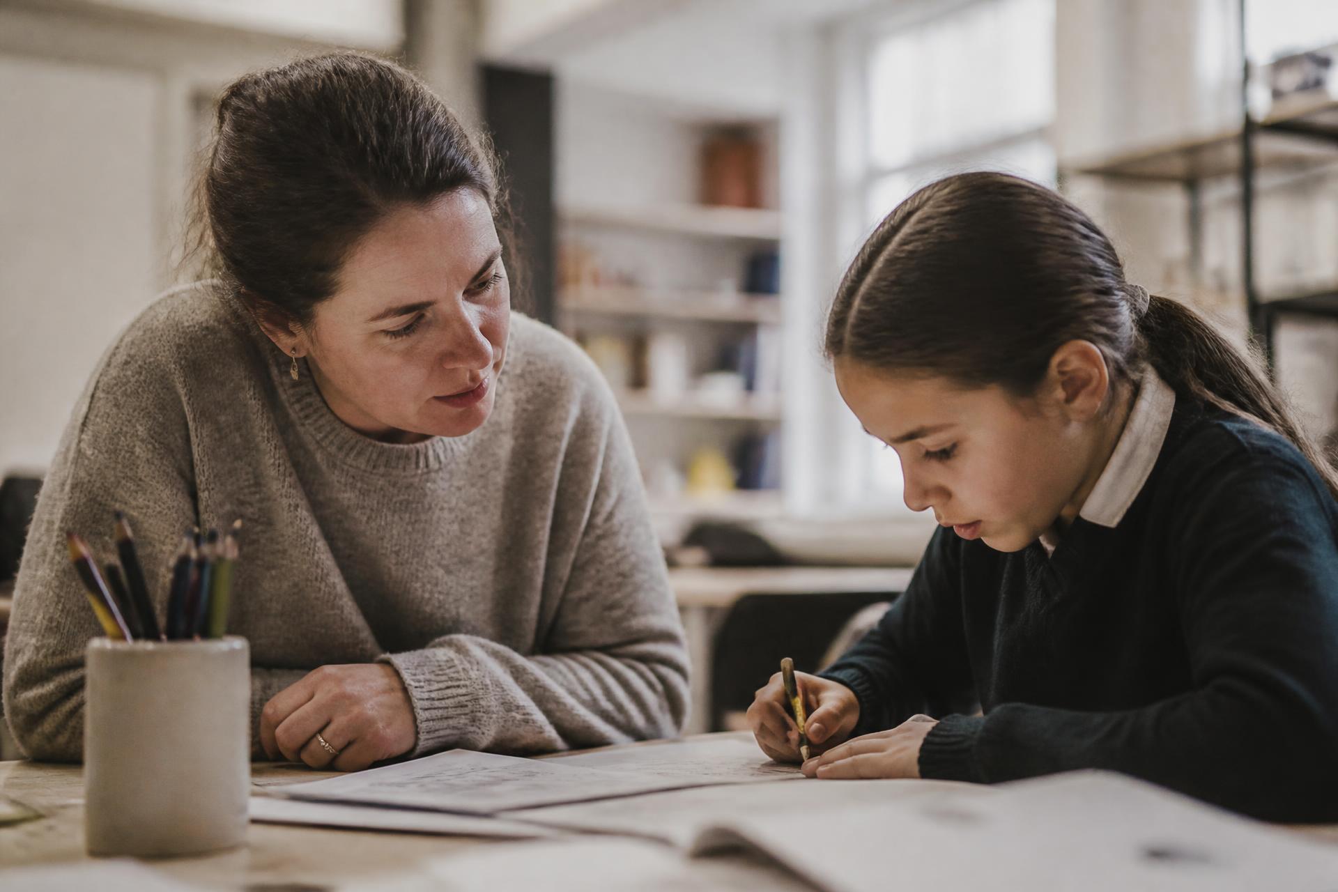 An educator working attentively with a student, observing and guiding their work